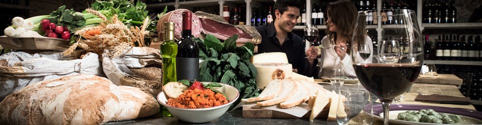 Un gruppo di persone è seduto a un tavolo e si gode una serata Eventi Pisa con un bicchiere di vino.