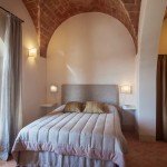 agriturismo-toscana-pisa (6) Una camera da letto con finestre ad arco e un letto.