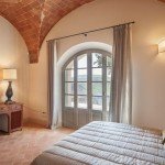 agriturismo-toscana-pisa (9) Una camera da letto con finestre ad arco e un letto.
