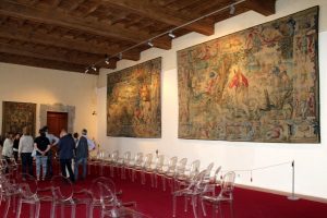 Una stanza con sedie e un arazzo appeso al muro è cosa da vedere a Pisa.
