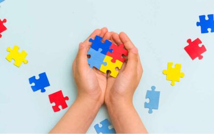 Due mani che tengono i pezzi del puzzle collegati sopra una superficie con parti del puzzle sparse.